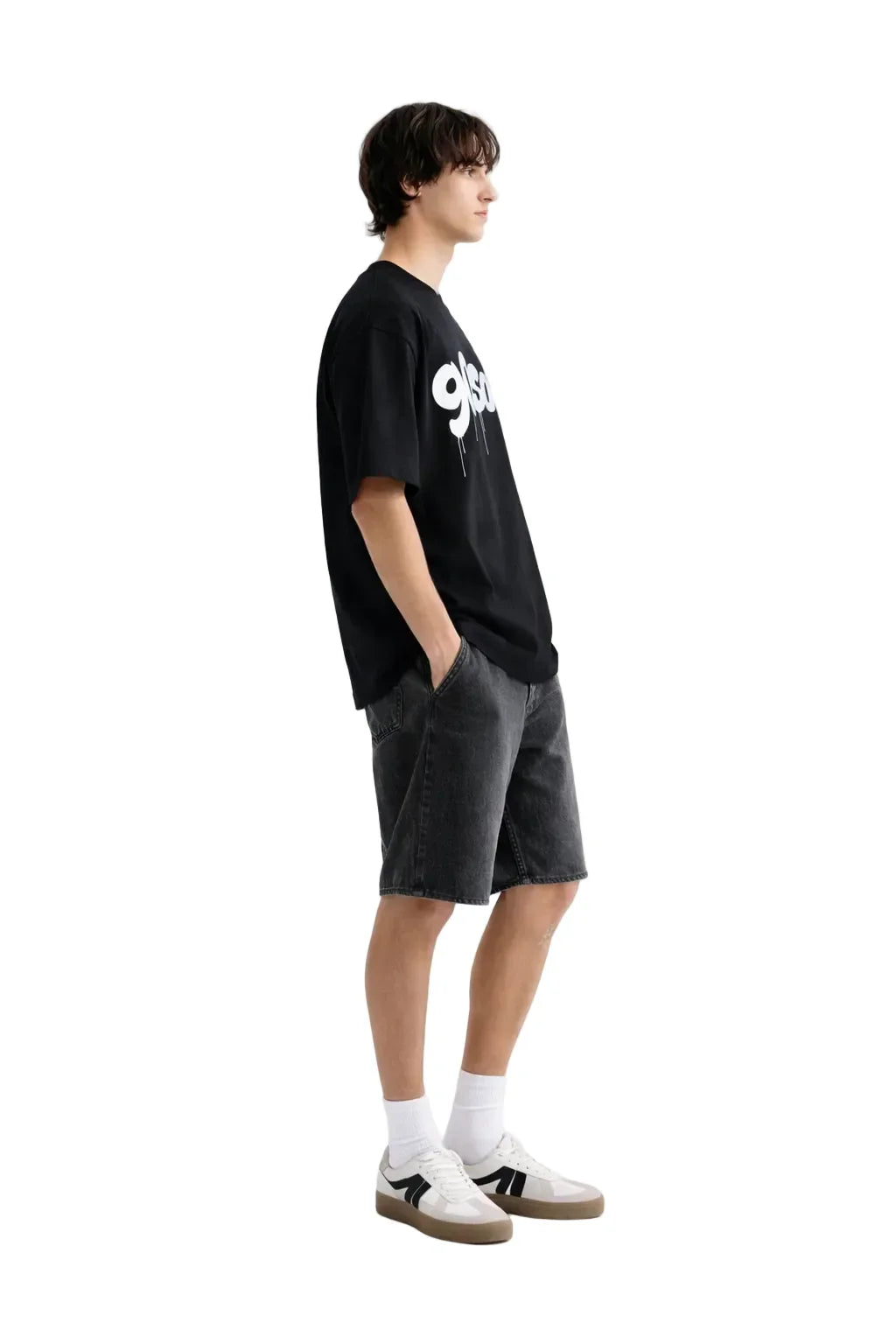 Man wearing oversized black graphic t-shirt, black denim shorts, and white sneakers