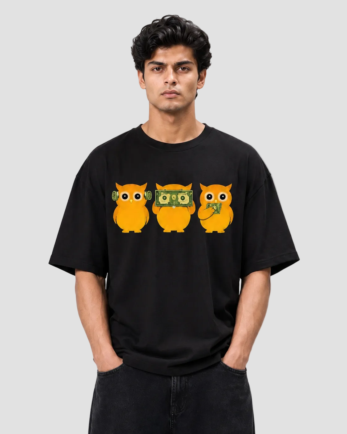A man wearing a black crewneck t-shirt with a graphic of three orange owls on the chest, standing against a light gray background.