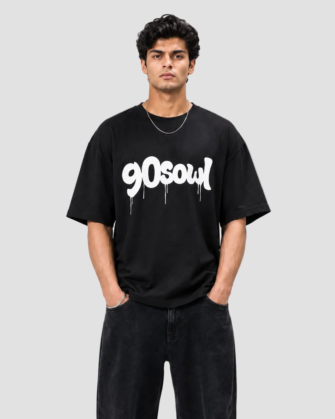 A man wearing a black crewneck t-shirt with a white '90soul' graphic printed across the chest, paired with black jeans, against a light gray studio background.