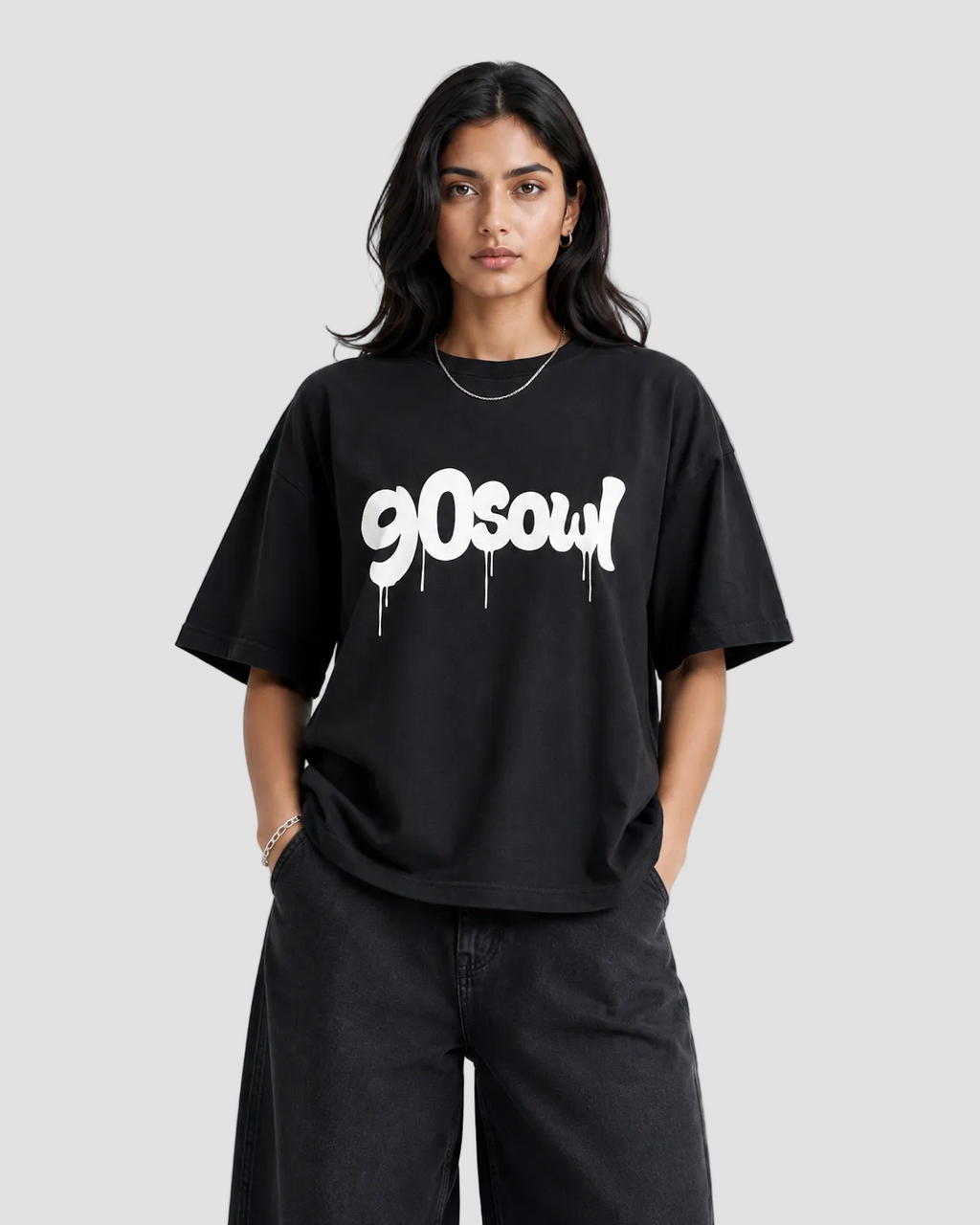 A woman modeling an oversized black t-shirt with a white '90soul' graphic printed across the chest, paired with black wide-leg jeans, against a plain light gray background.