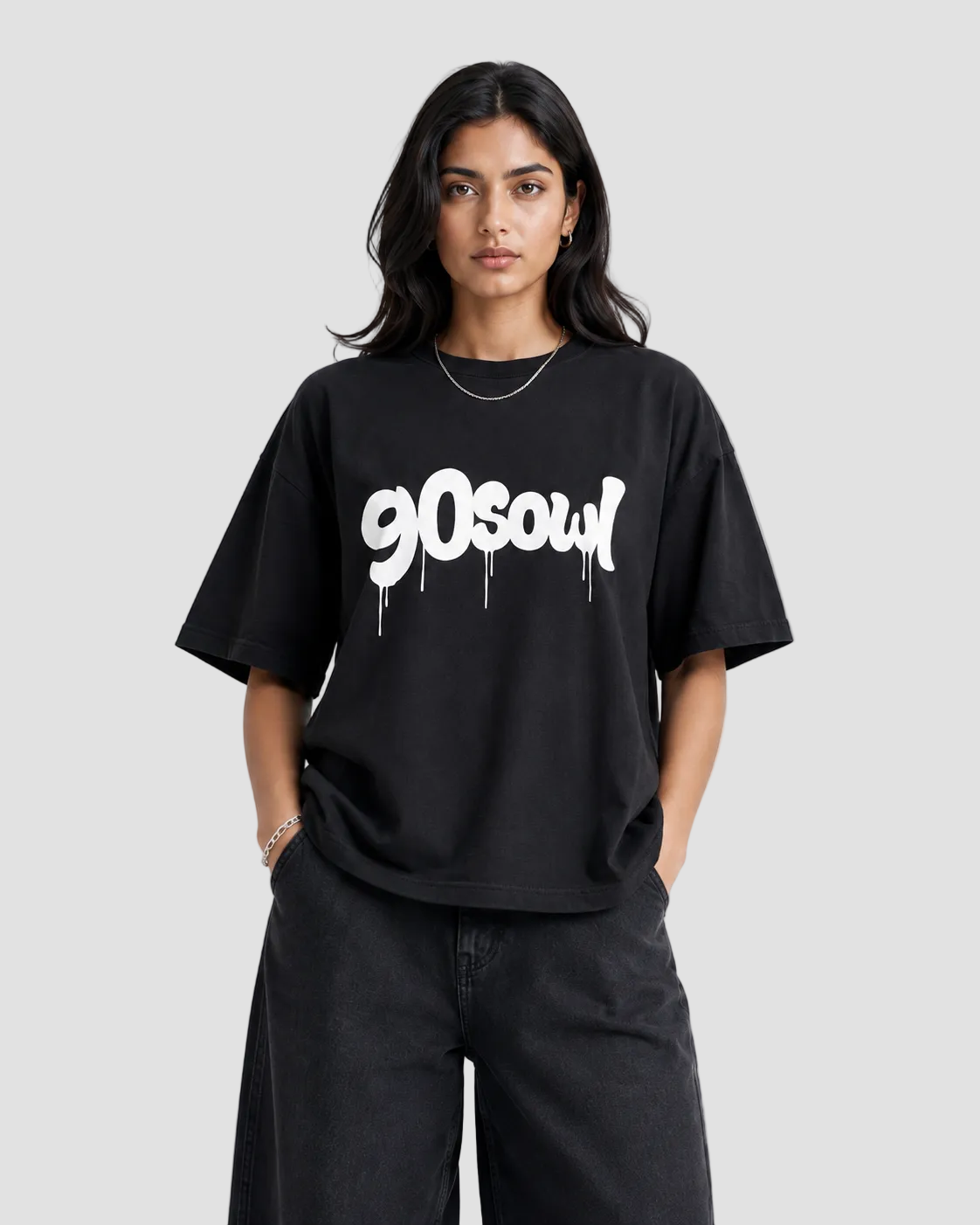 A woman modeling an oversized black t-shirt with a white '90soul' graphic printed across the chest, paired with black wide-leg jeans, against a plain light gray background.