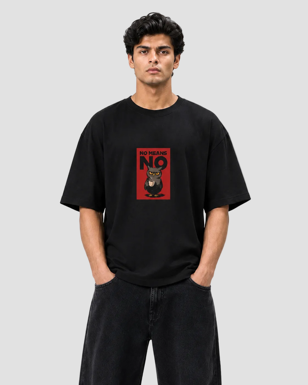 A man wearing a black t-shirt with a red graphic print on the chest that reads 'NOT YET ANO 2026' and features an owl illustration, paired with black jeans, against a light gray background.