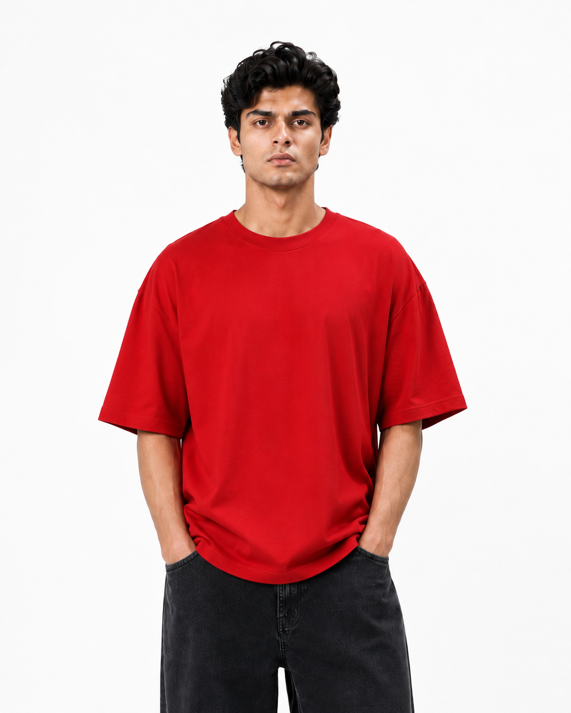 A man wearing a plain red short-sleeve crewneck t-shirt and dark gray jeans, standing against a solid white studio background.