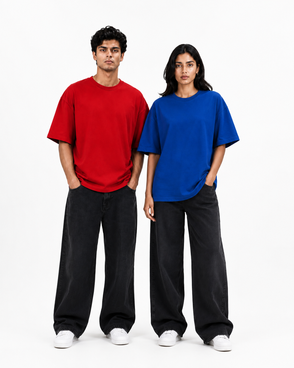 Two models standing side-by-side wearing oversized short-sleeve t-shirts in red and blue, paired with black wide-leg jeans and white sneakers, against a plain white studio background.