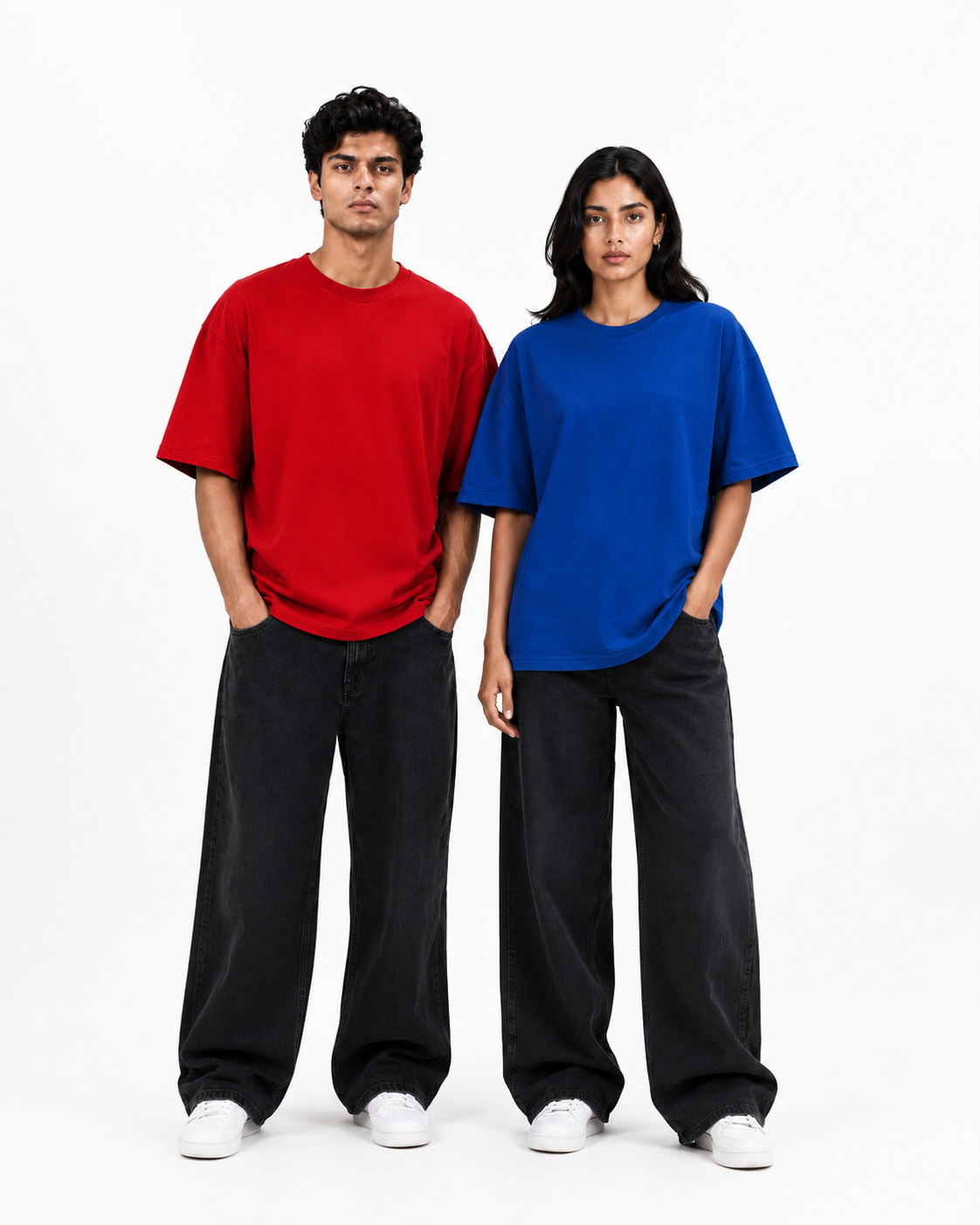 Two models standing side-by-side wearing oversized short-sleeve t-shirts in red and blue, paired with black wide-leg jeans and white sneakers, against a plain white studio background.