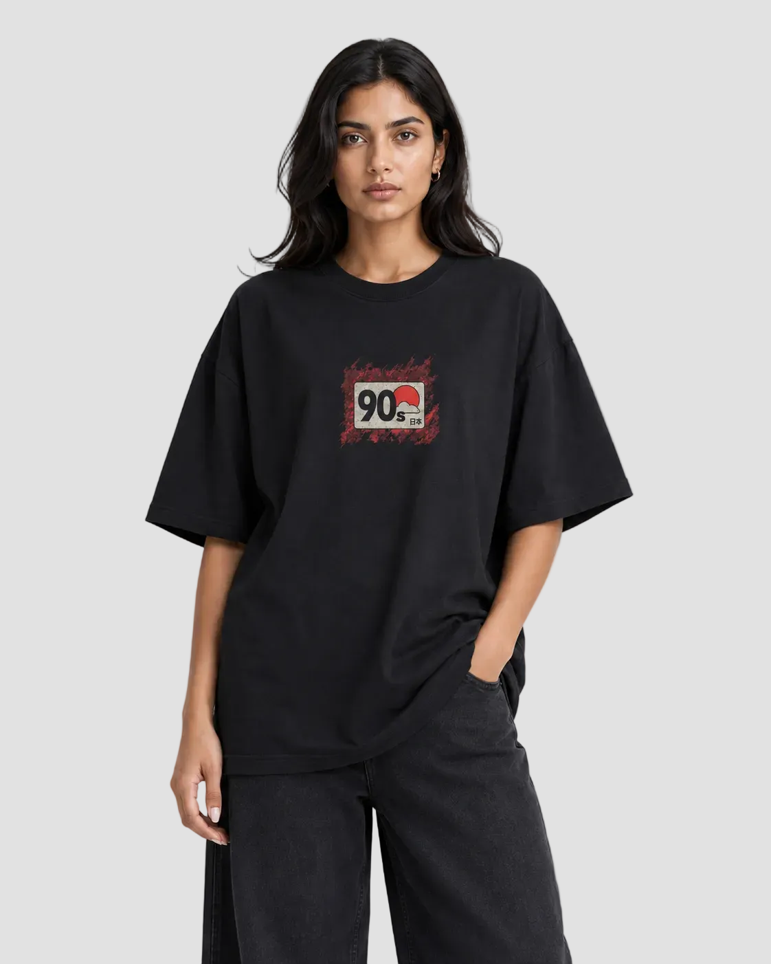 A woman modeling an oversized black t-shirt with a distressed red and white graphic on the chest, paired with black wide-leg pants, against a plain white studio background.