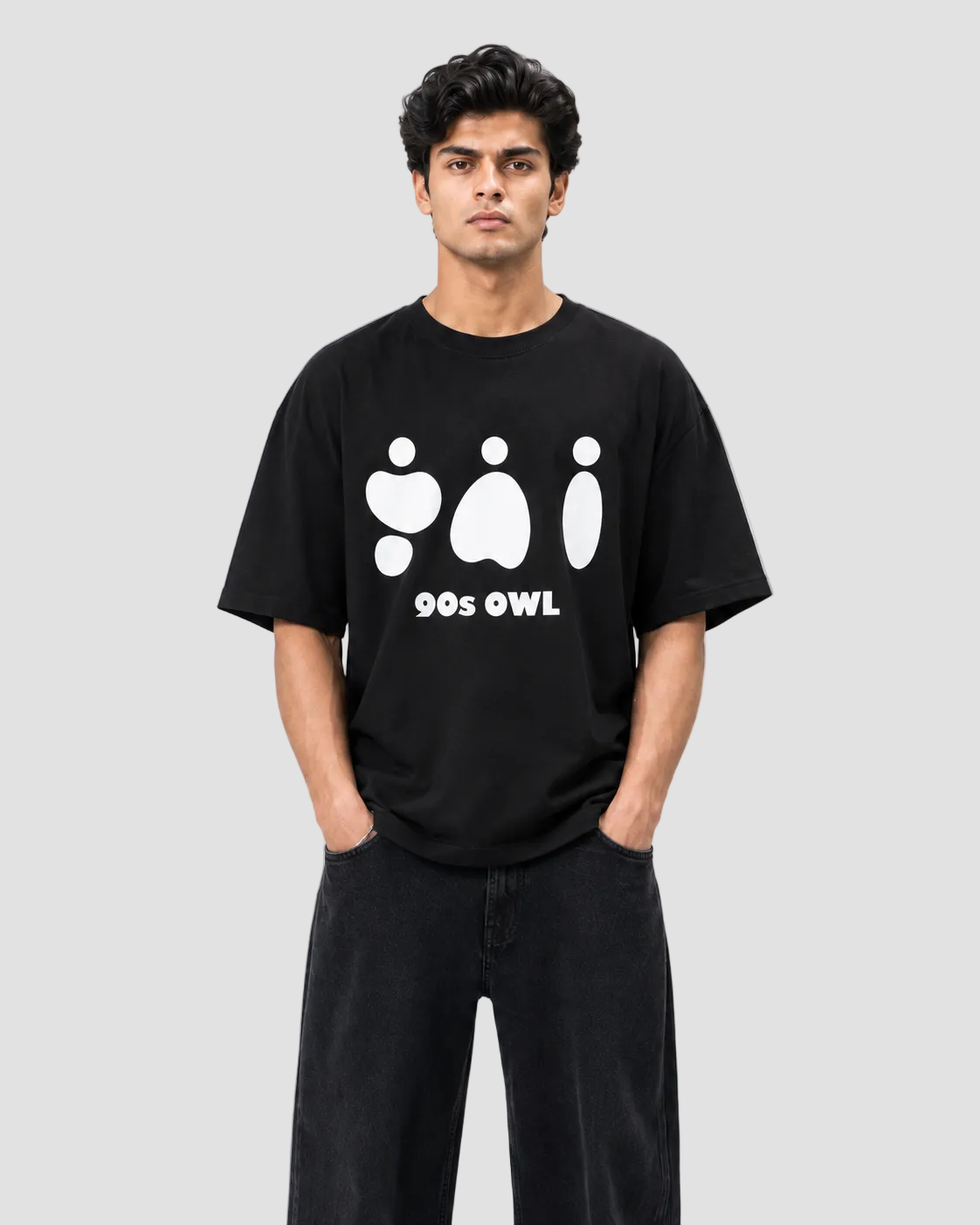 A man wearing a black short-sleeve t-shirt with a white graphic of three stylized owl shapes and the text '90s OWL' on the chest, paired with black pants, against a plain white background.
