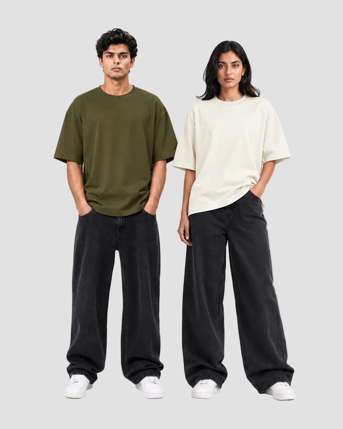 Two models standing against a light gray studio background, wearing oversized short-sleeve T-shirts in olive green and off-white, paired with loose black pants and white sneakers.