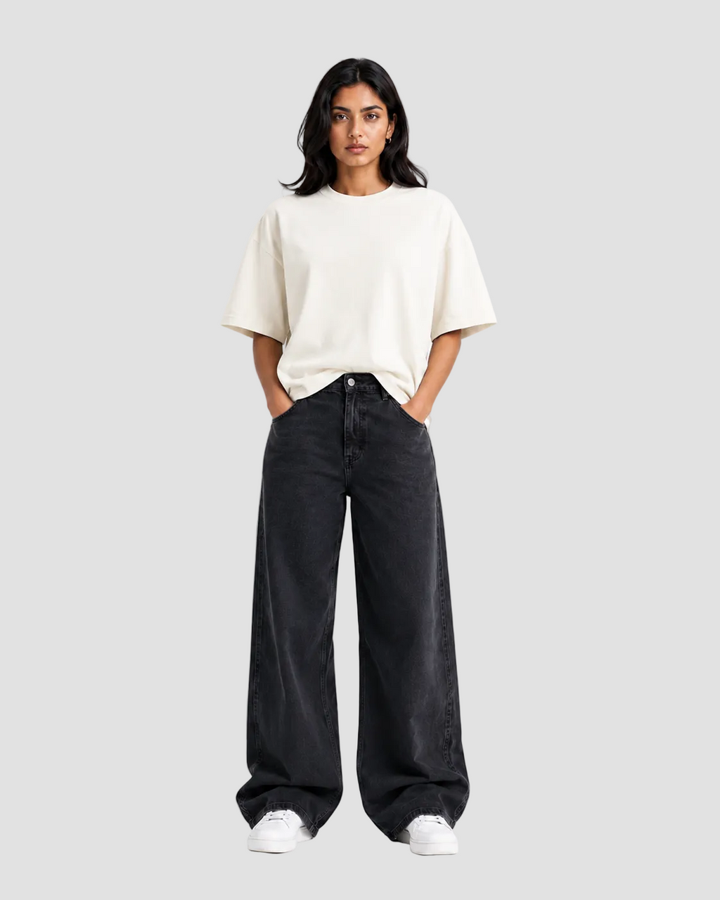 A woman modeling a cream-colored short-sleeve t-shirt and wide-leg black jeans against a plain white studio background.