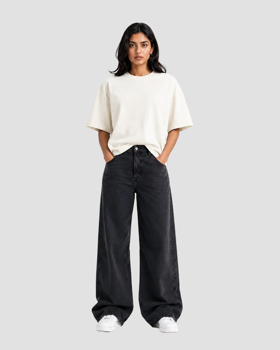 A woman modeling a cream-colored short-sleeve t-shirt and wide-leg black jeans against a plain white studio background.